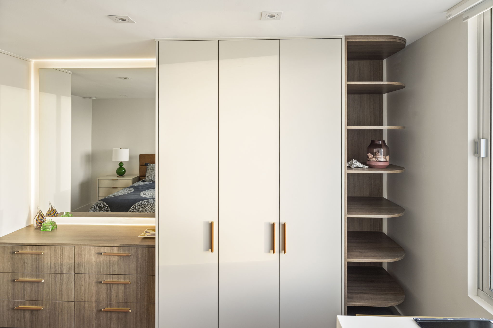 Custom walnut cabinetry with brass hardware and curved corner shelving